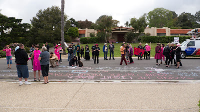 Protesters chalk the street in front of Neal Blue's mansion in La Jolla, CA.