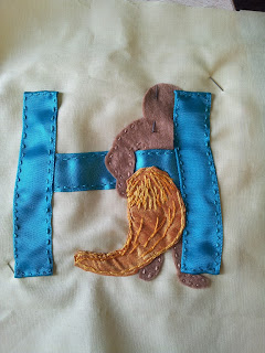 Letter H sewn down and lion skin sewn down and body sewn down. Head still hidden behind at this point.