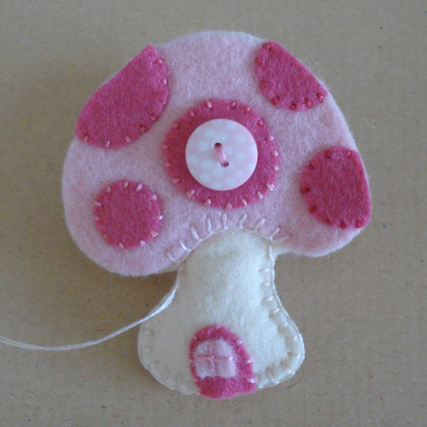 Sewing around pink toadstool home by hand blanket stitch