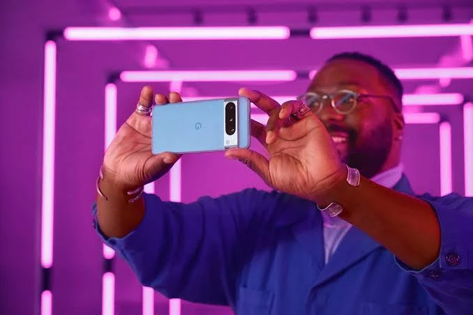 Google pixel 8 rear view in the hand of a man wearing blue shirt