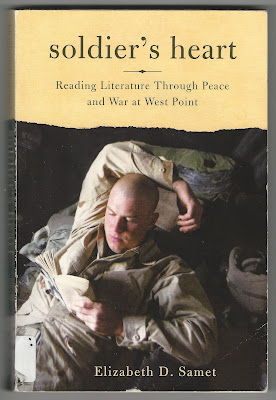 picture shows soldier in combat uniform laying down, relaxing, reading a book