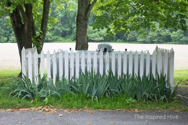 Great idea to hide a propane gas tank in the yard with a cute picket fence! Plus how to maintain the fence to keep it nice and bright.