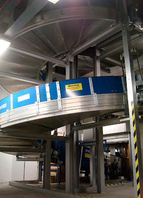 The spiral conveyor belt that brings bags upstairs to be scanned in the dark