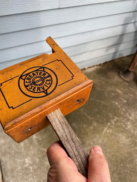 Photo of a metal container attached to a wooden garden stake