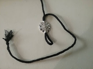 A black finger-loop lace with a pewter rose-shaped bead strung on it.