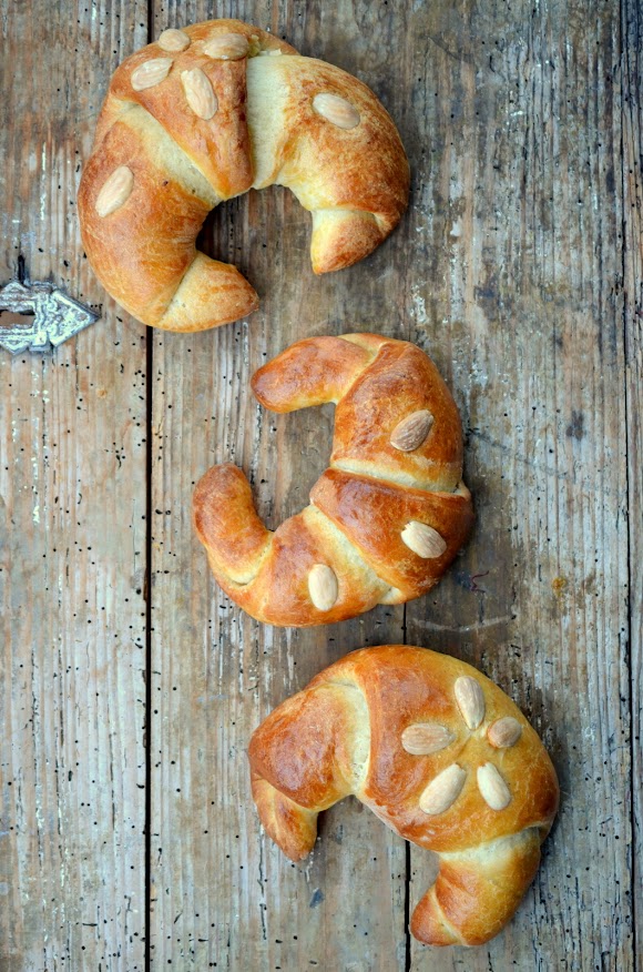 Goldbraune Kipferl sind mit weißen Mandeln verziert.