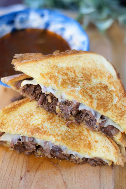 Birria Grilled Cheese with Au Jus Dipping Sauce on a board.