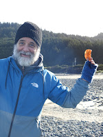 Bundled up man holding up a medium sized agate, which is backlit by the sun.