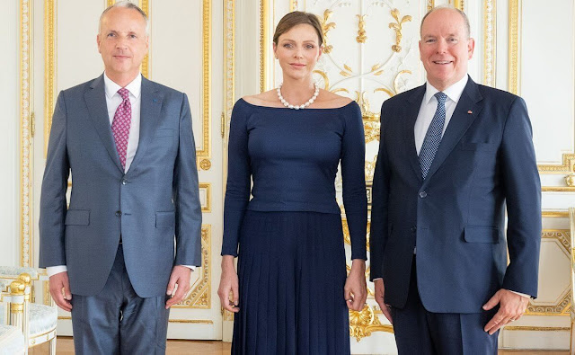 Princess Charlene wore a navy blue top by Akris, and a royal blue pleated maxi skirt by Akris. Pearl necklace