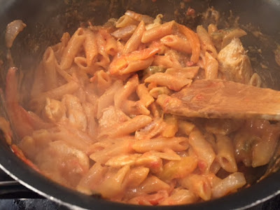 Pasta cooking in a pan with tomatoes and stock