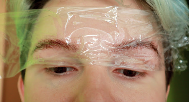 A photo of eyebrows with permanent gel applied and covered with transparent film