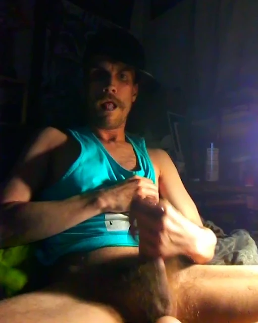 9/10 Oregonleatherboy gooning with tongue out wearing turquoise blue tank top with black leather hat