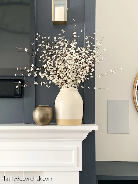 small white flowers in large vase on mantel