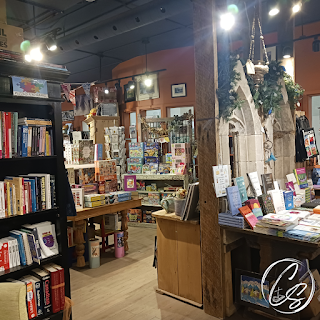 bookshelf on the left side of picture with middle table housing book-related puzzles and more book displays on the right side