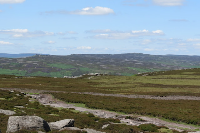 Moorland stretching out into the distance, with a glimpse of another escarpment on its edge.