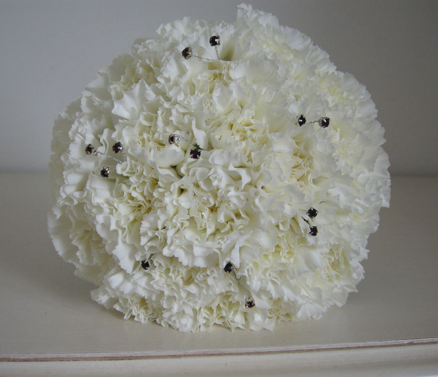 Bridesmaids' bouquets of massed ivory carnations with purple diamante 