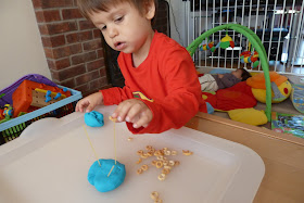 Child threading Cheerios onto spaghetti