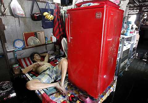 A Thai man rests inside his flooded house