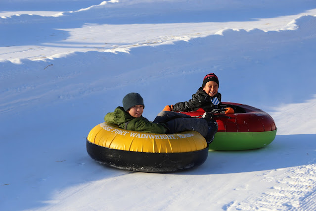 two kids riding snow tube down the hill