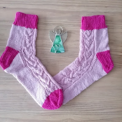ein Paar rosafarbene Socken und ein Engel aus Glas