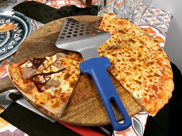 Wooden paddle topped with four slices of margherita pizza and two slices of Italian sausage and caramelised onion pizza, with a pizza cutter