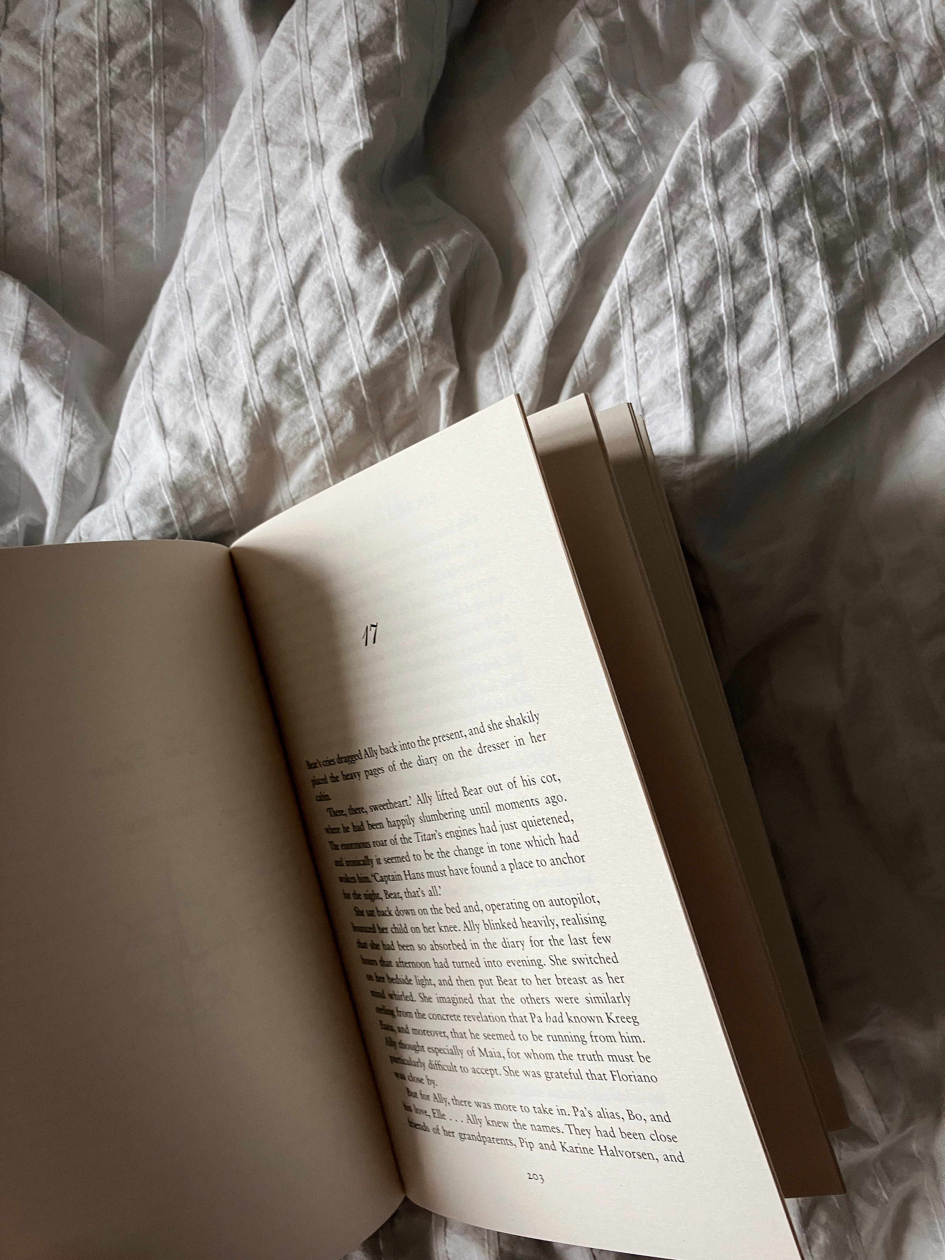 a book is open on a white bedspread, showing 'chapter 17'