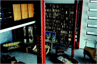 The bookcase with metal shelving has a ladder that slides along the length of the shelves. The cupboards and bookshelves were designed as screens to the second floor