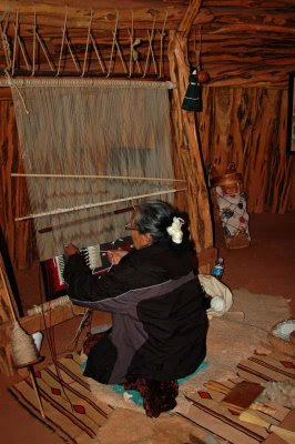 inside the hogan, a Navajo woman demonstrates rug weaving