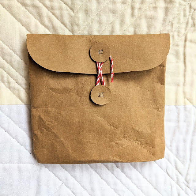 A paper fabric pouch with 2 circles sewn on and a string closure, like an envelope