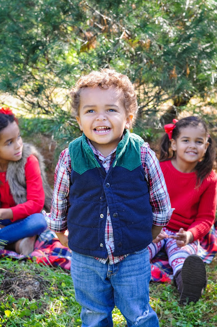 siblings taking pictures at a Christmas tree farm