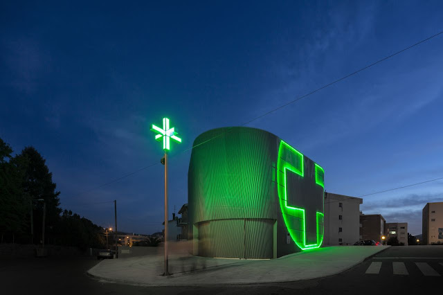 Picture of small modern pharmacy building at night as seen from the street