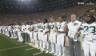 Packers players are joined by fans in linking arms during national anthem 