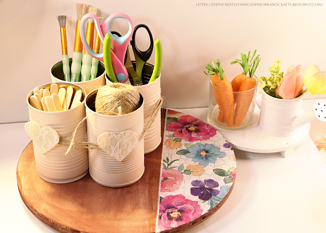 Metal can organizer with paintbrushes, cutting tools, twine, and craft sticks displayed on a table