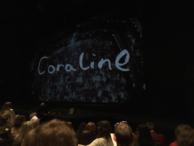 photo shows curtain reading 'Coraline' and projected image of the auditorium and audience