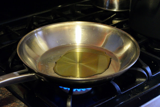 A skillet on the stove with oil in it.