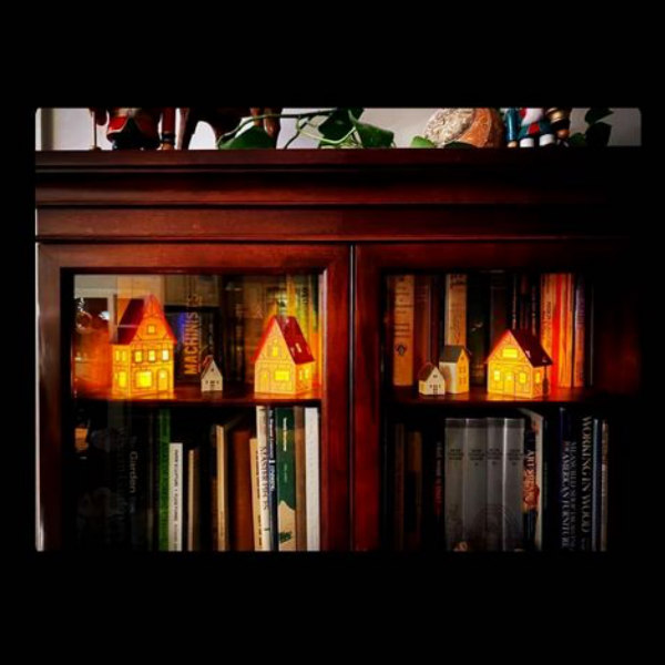tiny lighted paper houses displayed in dark wood bookcase