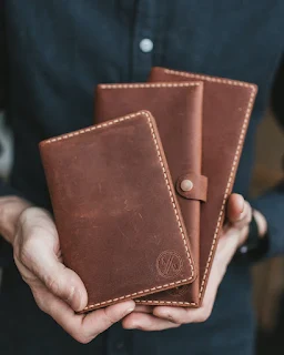 A Man Holding Three Brown Leather Wallets