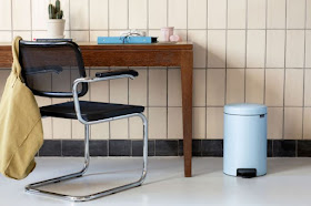 small light blue pedal waste bin on the floor next to a desk