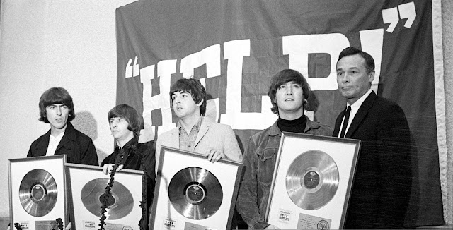 Los Beatles muestran sus discos de oro durante una conferencia de prensa para la película Help! De 1965