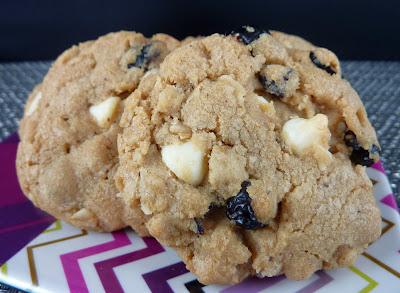 Cookies with browned butter, cranberries, oats, and cream cheese chips, photographed on a pink zig-zag plate