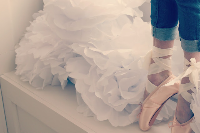 Beautiful soft feminine dancer in pointe shoes with white tissue pouf blooms