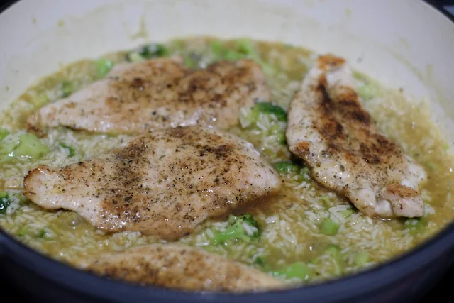 The fully cooked chicken being placed on top of the broccoli, chicken, and rice mixture.  