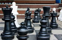 Large toddler-sized chess pieces on a giant chess board