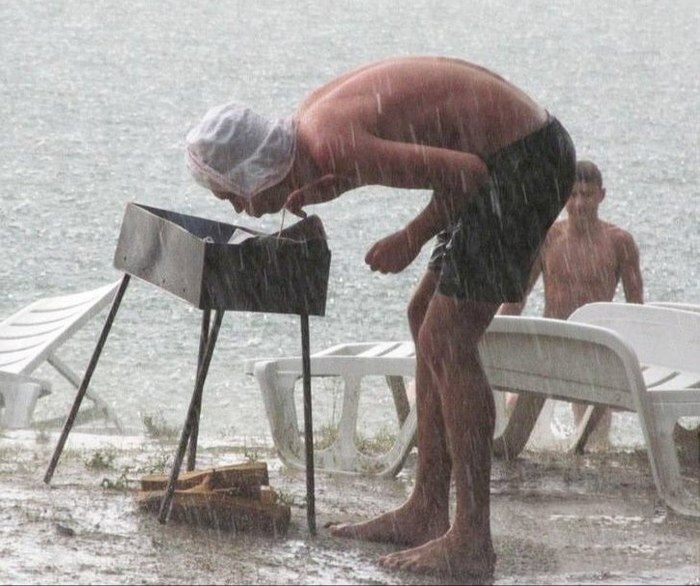 Mann versucht bei strömendem Regen den Grill anzufeuern lustig