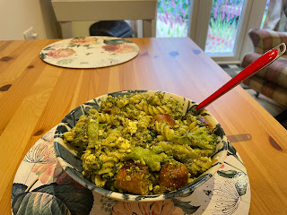 A bowl of pesto pasta with feta and veggie sausages.