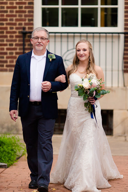 The bride and groom met in college, and have been together for three and a half years.  Maggie said that walking down the aisle towards Jordan was the best part of the day, knowing that they were surrounded by the love and support of friends and family.  She said, “As I walked towards him, Jordan and I were both tearing up and we couldn’t look away from each other.”  Jordan said that since he was “anxious all day, to the point of feeling sick,” the first look was the most memorable part of the day.  He said, “The moment I saw Maggie, I felt 100% relieved, and it made the hours before the ceremony so much more enjoyable.”    The Festivities Event Center in El Reno, OK, was the perfect wedding backdrop, with 10’ windows, a whole second floor to get ready in, and a romantic setting for the outdoor nuptial.  The bride looked “drop-dead gorgeous” in her lace-embroidered, strapless, wedding gown, followed by her bridesmaids, dressed in individually designed gowns in soft hues of dusty rose.  Each bridesmaid had a spring floral bouquet, similar to the bride’s bouquet of pastel pink roses and lilies.    After the couple exchanged wedding vows, pictures of the family and wedding party were taken, and it was time to celebrate!  First dances came next, then guests were invited to enjoy a Mexican buffet.  Dessert included the gorgeous wedding cake, chocolate groom’s cake, and assorted, homemade cookies and pastries.  The evening came to a close as the guests sent the star-gazed couple off with sparklers!  The newly married couple escaped to Cozumel and Yucatan Progreso for their honeymoon.  