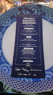 um prato branco com borda azul e o menu de um jantar num folheto azul ao centro