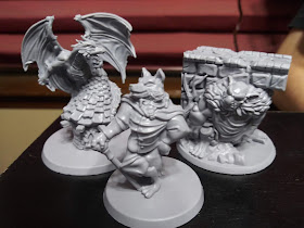 Three of the monster minis. One is the dragon, standing on top of one of the pigs' houses with his wings spread wide. Another is the big bad wolf, standing with a cane propping him up. The third is the bridge troll, hunkered underneath a segment of a bridge.