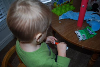 little kid glueing eyes onto a toilet paper roll