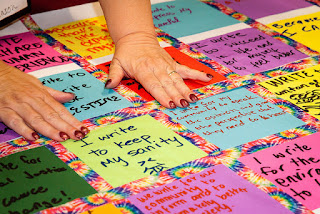 A woman's hands hold down squares of paper as they are taped into a quilt.